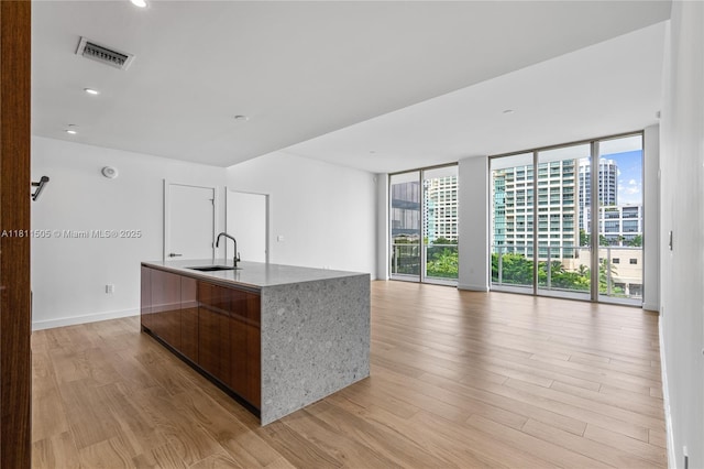 2678 Tigertail Ave Unit 513, Coconut Grove, FL 33133 - kitchen featuring a sink, light wood-style flooring, plenty of natural light, an island with sink, and a wall of windows