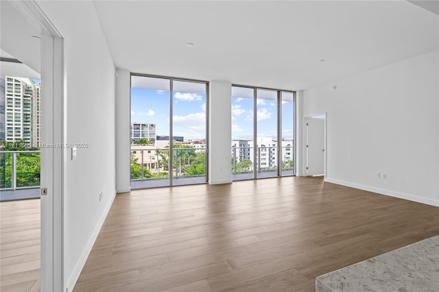 2678 Tigertail Ave Unit 513, Coconut Grove, FL 33133 - unfurnished room with wood finished floors, a wall of windows, healthy amount of natural light, and baseboards