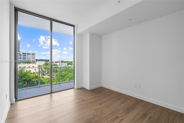 2678 Tigertail Ave Unit 513, Coconut Grove, FL 33133 - unfurnished room featuring healthy amount of natural light, wood finished floors, a wall of windows, baseboards, and a view of city