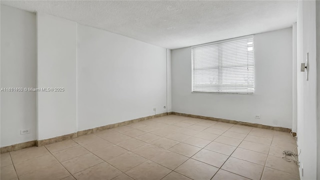 3660 NE 166th St Unit 603, North Miami Beach, FL 33160 - spare room featuring a textured ceiling, light tile patterned flooring, and baseboards