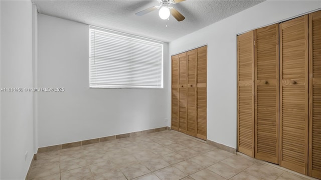 3660 NE 166th St Unit 603, North Miami Beach, FL 33160 - unfurnished bedroom with a textured ceiling, two closets, a ceiling fan, baseboards, and light tile patterned floors