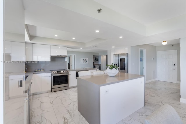 812 N Ocean Blvd Unit 405, Pompano Beach, FL 33062 - kitchen featuring stainless steel appliances, modern cabinets, a tray ceiling, white cabinets, and light marble finish floors