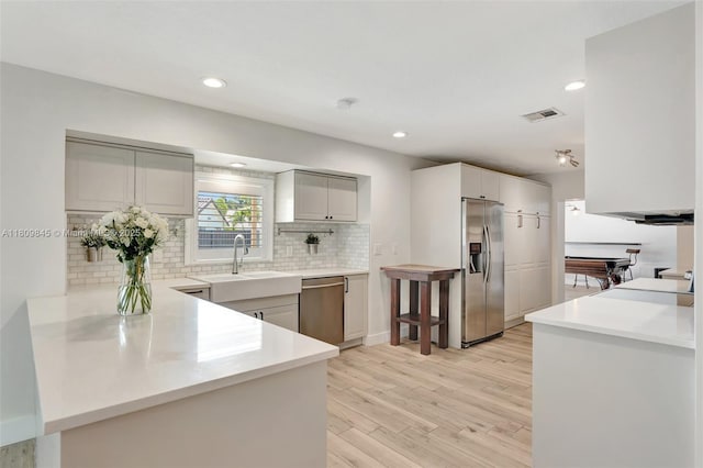 651 E Lake Dasha Dr, Plantation, FL 33324 - kitchen featuring stainless steel appliances, a sink, backsplash, light wood-style flooring, and light countertops