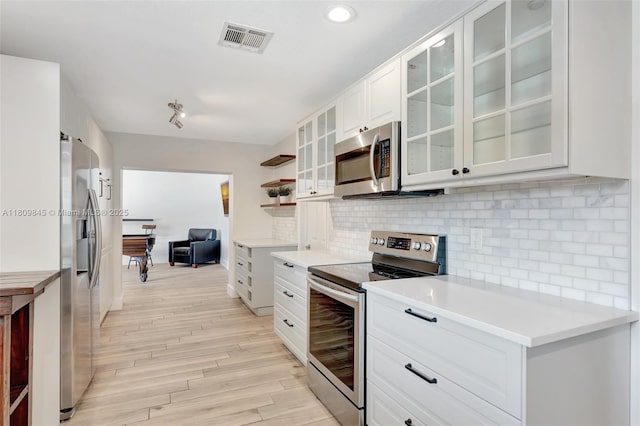 651 E Lake Dasha Dr, Plantation, FL 33324 - kitchen featuring appliances with stainless steel finishes, light wood-type flooring, tasteful backsplash, light countertops, and white cabinetry