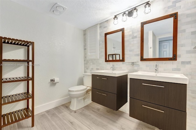 651 E Lake Dasha Dr, Plantation, FL 33324 - bathroom with wood finished floors, two vanities, toilet, baseboards, and backsplash