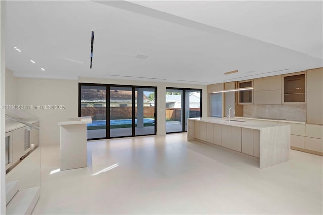 330 SW 19th Rd, Miami, FL 33129 - kitchen with modern cabinets, a center island with sink, light countertops, a wall of windows, and decorative backsplash