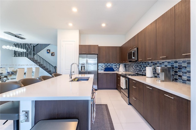 4366 SW 174th Ave, Miramar, FL 33029 - kitchen with appliances with stainless steel finishes, a sink, a kitchen bar, light countertops, and decorative backsplash
