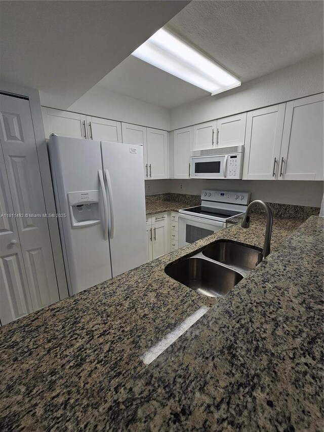 8475 SW 156th Ct Unit 321, Miami, FL 33193 - kitchen featuring white appliances, white cabinetry, a sink, and dark stone counters