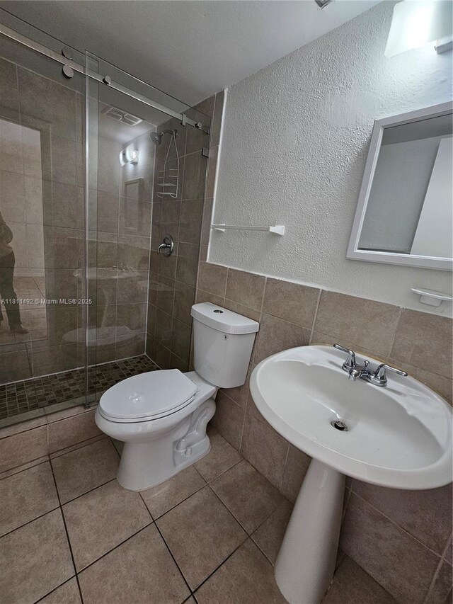 8475 SW 156th Ct Unit 321, Miami, FL 33193 - bathroom with toilet, tile walls, a shower stall, tile patterned flooring, and a textured wall