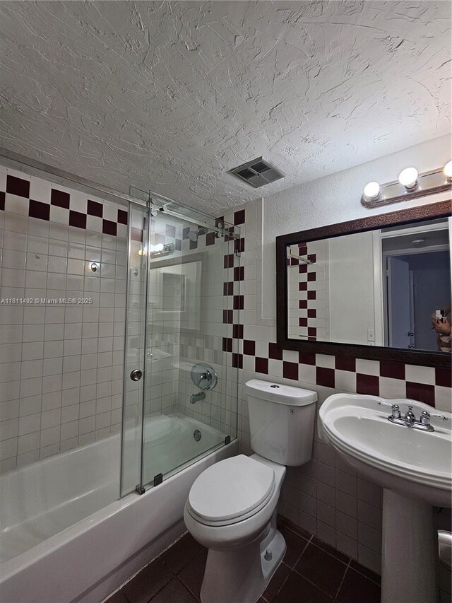 8475 SW 156th Ct Unit 321, Miami, FL 33193 - full bath with a textured ceiling, shower / bath combination with glass door, tile patterned flooring, toilet, and tile walls