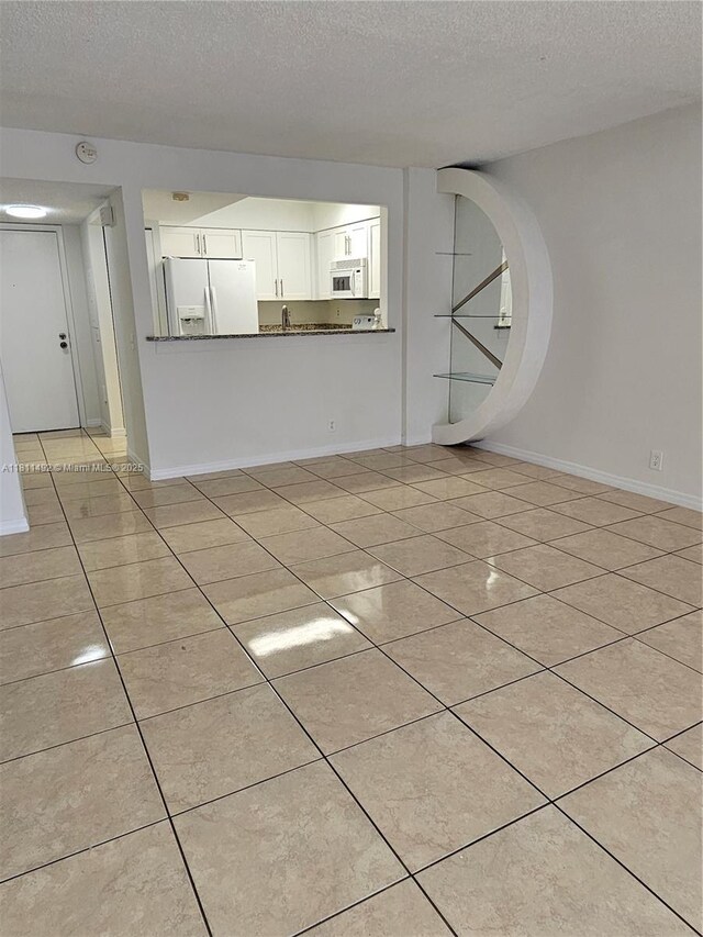 8475 SW 156th Ct Unit 321, Miami, FL 33193 - unfurnished living room with a textured ceiling, light tile patterned floors, baseboards, and a sink