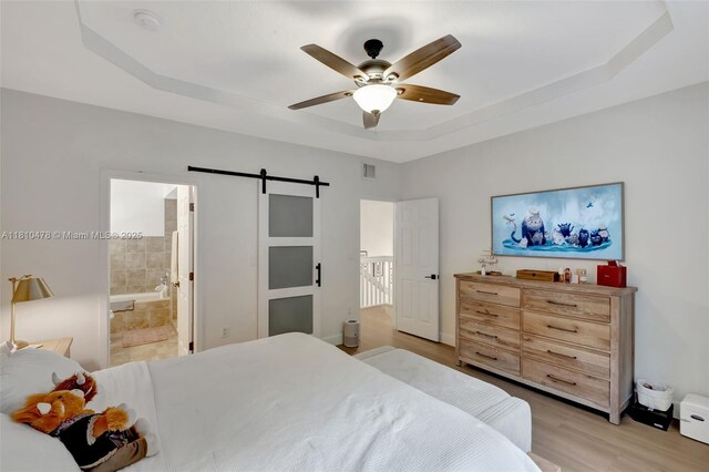 4413 NW 97th Pl, Doral, FL 33178 - bedroom with a raised ceiling, a barn door, light wood-style flooring, ensuite bath, and ceiling fan