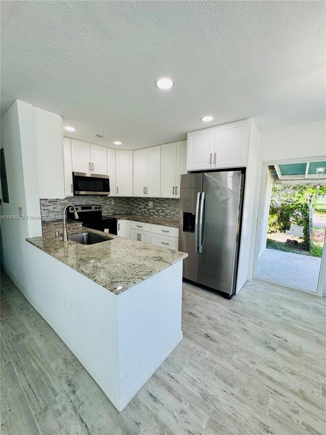 4341 NW 59th St, North Lauderdale, FL 33319 - kitchen with appliances with stainless steel finishes, light stone counters, a textured ceiling, a peninsula, and white cabinetry