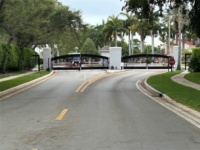11920 SW 20th St, Miramar, FL 33025 - view of asphalt street featuring a gate, sidewalks, curbs, and a gated entry