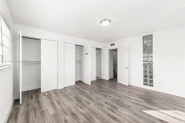 1461 NE 150th St Unit 103, Miami, FL 33161 - unfurnished bedroom featuring multiple closets, wood finished floors, and baseboards