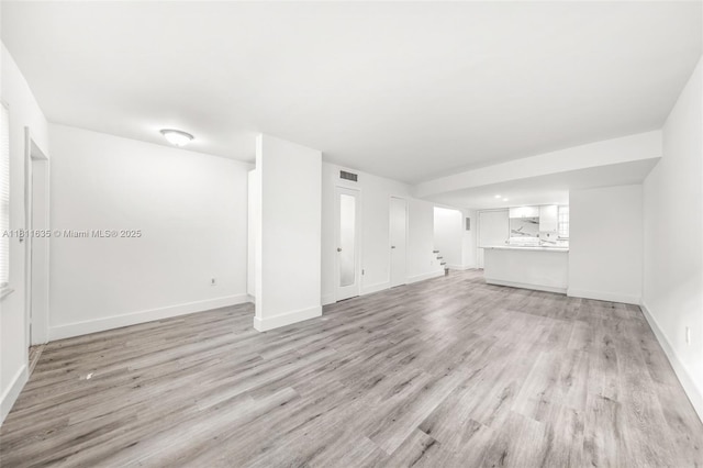 1461 NE 150th St Unit 103, Miami, FL 33161 - unfurnished living room with baseboards, light wood finished floors, and stairs