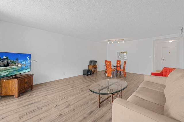 500 NE 12th Ave Unit 407, Hallandale Beach, FL 33009 - living room featuring light wood finished floors, a textured ceiling, rail lighting, and baseboards