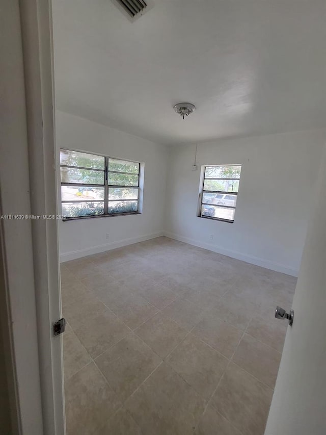 640-642 NW 77th St, Miami, FL 33150 - empty room with plenty of natural light, light tile patterned flooring, and baseboards