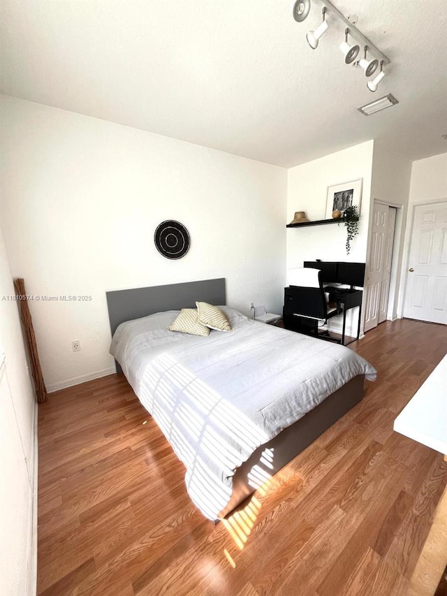 5670 NW 116th Ave Unit 212, Doral, FL 33178 - bedroom featuring track lighting, wood finished floors, and baseboards