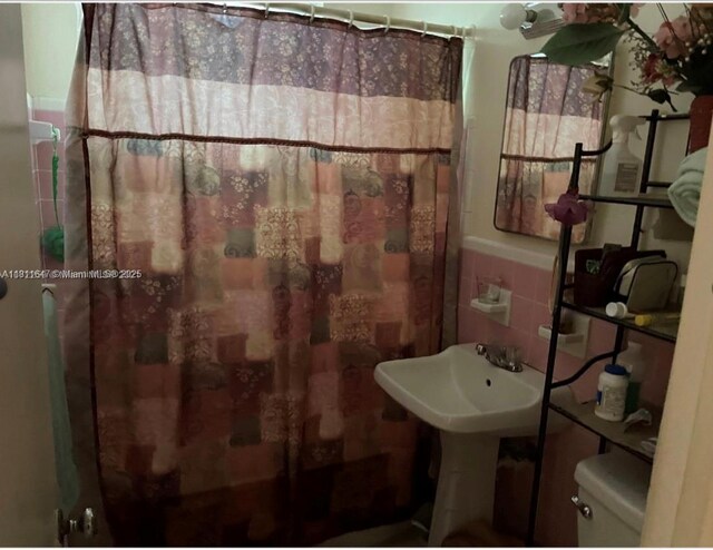 1570 NE 130th St, North Miami, FL 33161 - full bathroom featuring toilet, a shower with shower curtain, wainscoting, and tile walls