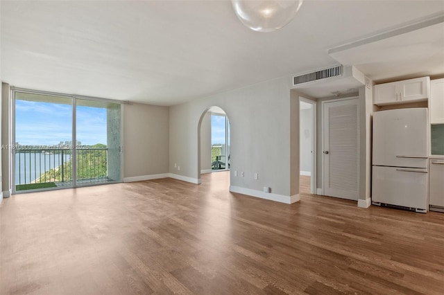 150 SE 25th Rd Unit 10K, Miami, FL 33129 - unfurnished living room with arched walkways, wood finished floors, healthy amount of natural light, baseboards, and expansive windows