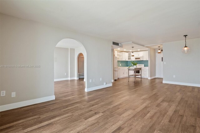 150 SE 25th Rd Unit 10K, Miami, FL 33129 - unfurnished living room featuring arched walkways, wood finished floors, and baseboards