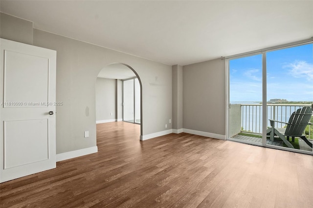150 SE 25th Rd Unit 10K, Miami, FL 33129 - spare room with arched walkways, wood finished floors, expansive windows, baseboards, and a water view