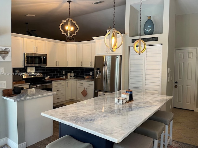 20390 NW 2nd St, Pembroke Pines, FL 33029 - kitchen with stainless steel appliances, backsplash, a breakfast bar, white cabinets, and high vaulted ceiling