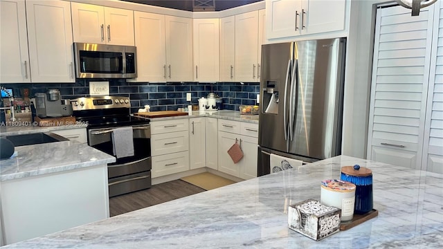 20390 NW 2nd St, Pembroke Pines, FL 33029 - kitchen featuring appliances with stainless steel finishes, white cabinets, light stone countertops, wood finished floors, and tasteful backsplash