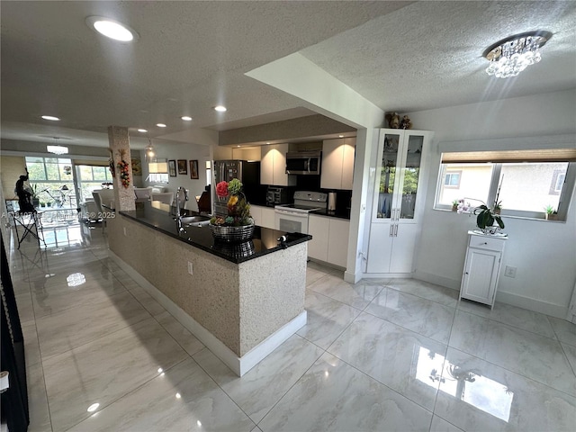 13700 SW 14th St Unit 412D, Pembroke Pines, FL 33027 - kitchen with appliances with stainless steel finishes, white cabinets, baseboards, a sink, and dark countertops