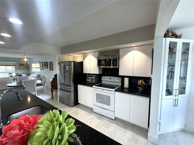 13700 SW 14th St Unit 412D, Pembroke Pines, FL 33027 - kitchen with appliances with stainless steel finishes, dark countertops, light marble finish flooring, white cabinets, and a textured ceiling