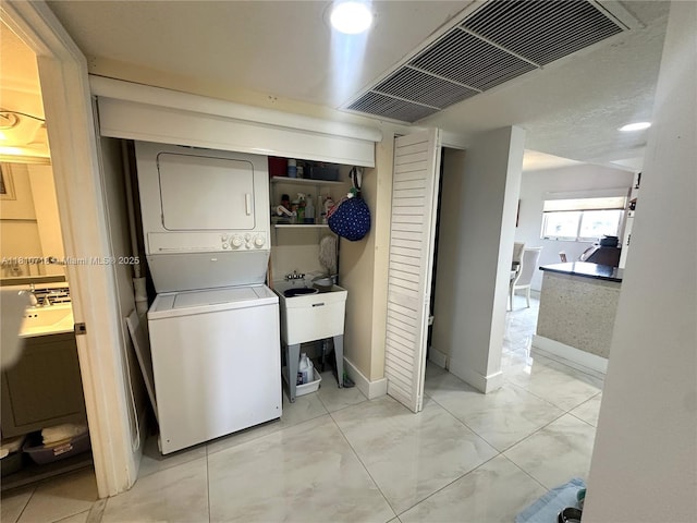 13700 SW 14th St Unit 412D, Pembroke Pines, FL 33027 - laundry area featuring stacked washer / dryer, marble finish floors, baseboards, and a sink