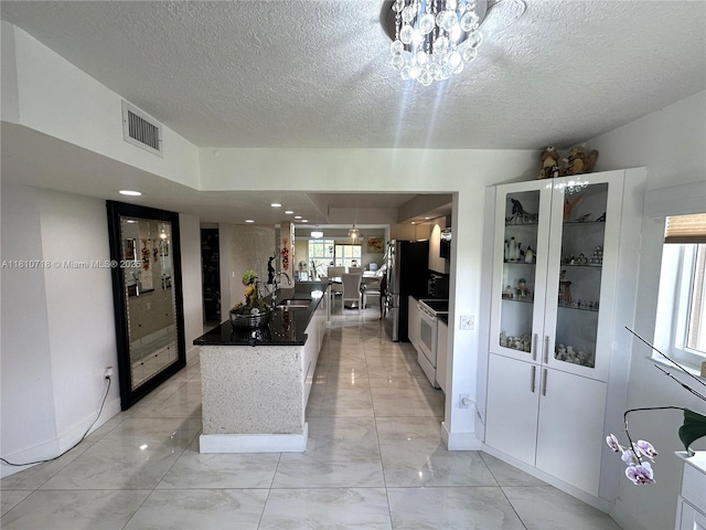 13700 SW 14th St Unit 412D, Pembroke Pines, FL 33027 - kitchen featuring white electric stove, light marble finish floors, freestanding refrigerator, a textured ceiling, and a sink