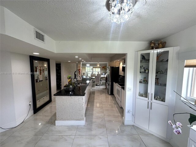 13700 SW 14th St Unit 412D, Pembroke Pines, FL 33027 - kitchen with light marble finish floors, freestanding refrigerator, a textured ceiling, and white cabinets