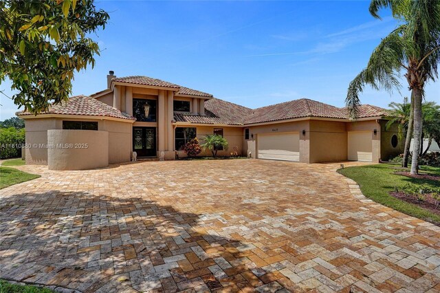 10427 Stonebridge Blvd, Boca Raton, FL 33498 - mediterranean / spanish house with a chimney, stucco siding, a garage, and a tile roof