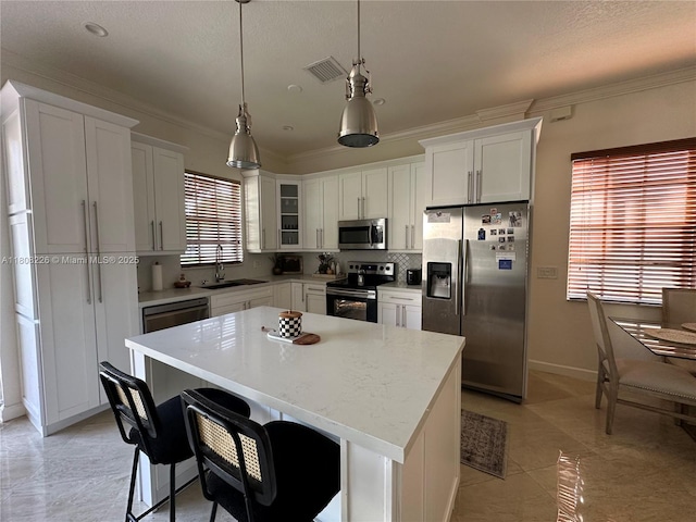 12464 SW 42nd St, Miramar, FL 33027 - kitchen featuring stainless steel appliances, a sink, ornamental molding, white cabinets, and a center island