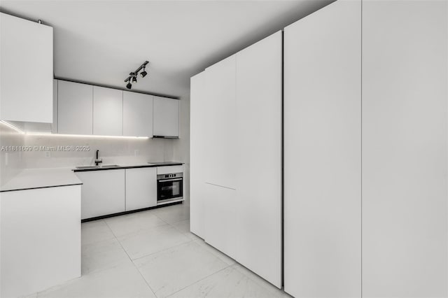 770 NE 69th St Unit 6C, Miami, FL 33138 - kitchen featuring stainless steel oven, a sink, white cabinets, and modern cabinets