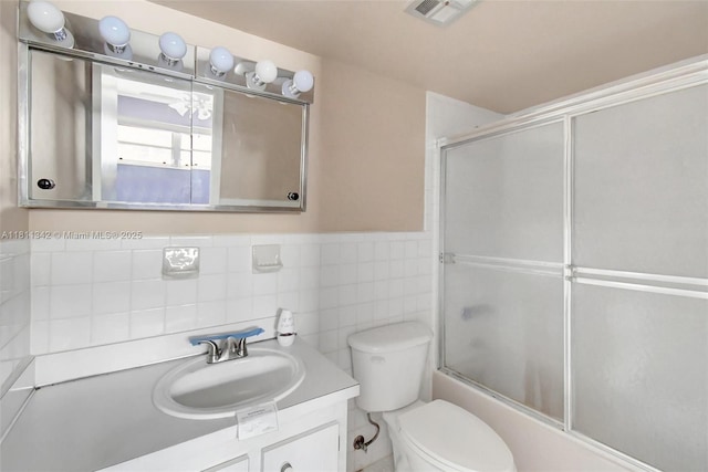 6211 SW 37th St Unit 211, Davie, FL 33314 - bathroom with vanity, shower / bath combination with glass door, toilet, a wainscoted wall, and tile walls