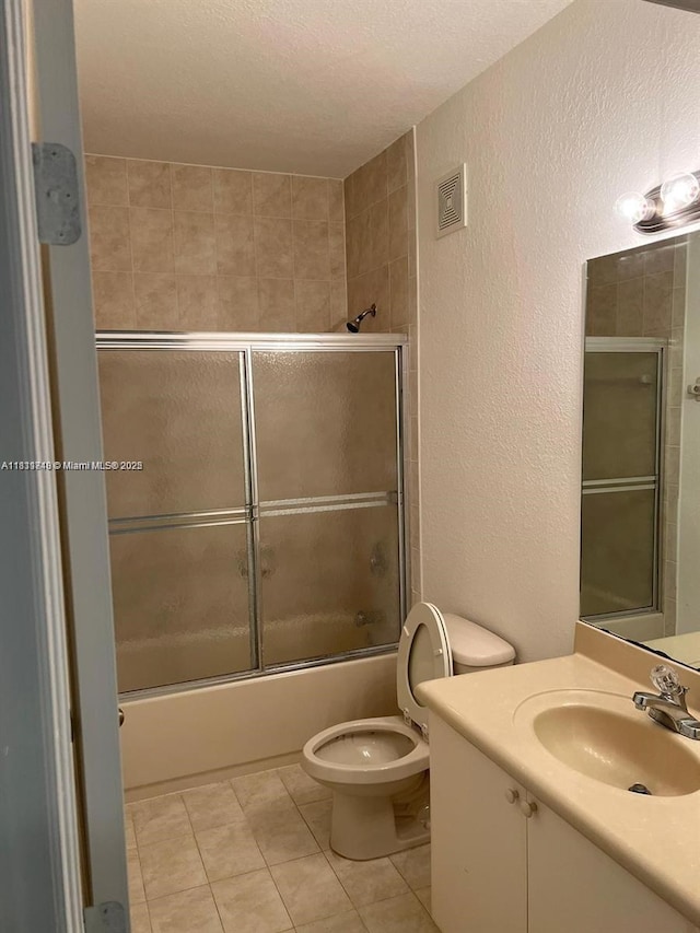 2758 SE 17th Ave Unit 102, Homestead, FL 33035 - bathroom featuring a textured wall, vanity, toilet, combined bath / shower with glass door, and tile patterned flooring