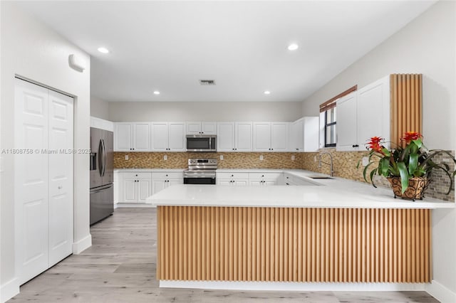 24083 SW 112th Pl, Homestead, FL 33032 - kitchen with appliances with stainless steel finishes, a peninsula, light wood-type flooring, tasteful backsplash, and recessed lighting