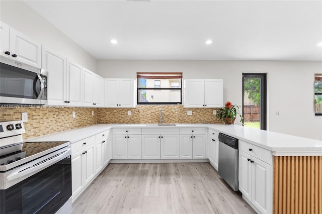 24083 SW 112th Pl, Homestead, FL 33032 - kitchen with appliances with stainless steel finishes, a peninsula, light countertops, light wood-type flooring, and tasteful backsplash