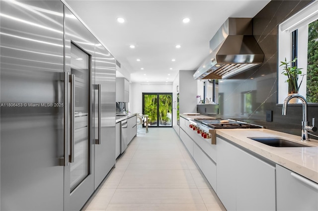 5970 Alton Rd, Miami Beach, FL 33140 - kitchen featuring stainless steel appliances, wall chimney exhaust hood, modern cabinets, a sink, and healthy amount of natural light