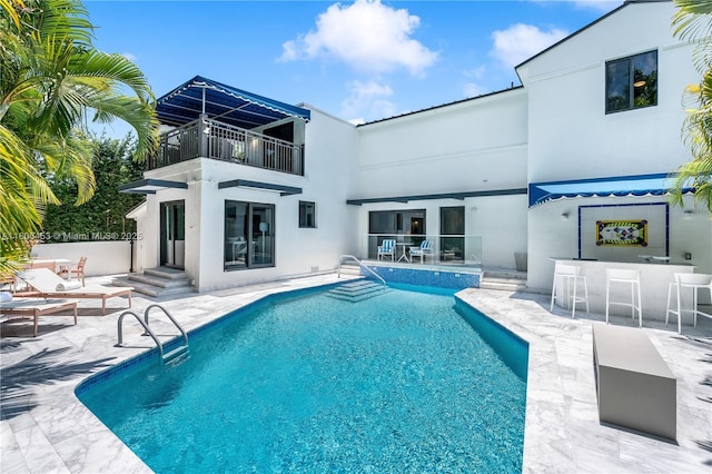 5970 Alton Rd, Miami Beach, FL 33140 - back of property with a balcony, a patio, an outdoor pool, and stucco siding