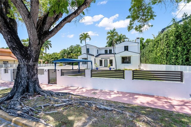 5970 Alton Rd, Miami Beach, FL 33140 - back of property with a fenced front yard, stucco siding, and a chimney