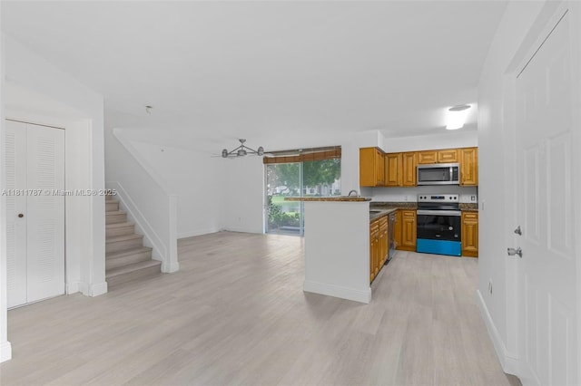 12154 Saint Andrews Pl Unit 112, Miramar, FL 33025 - kitchen with appliances with stainless steel finishes, light wood-style flooring, brown cabinets, and a peninsula