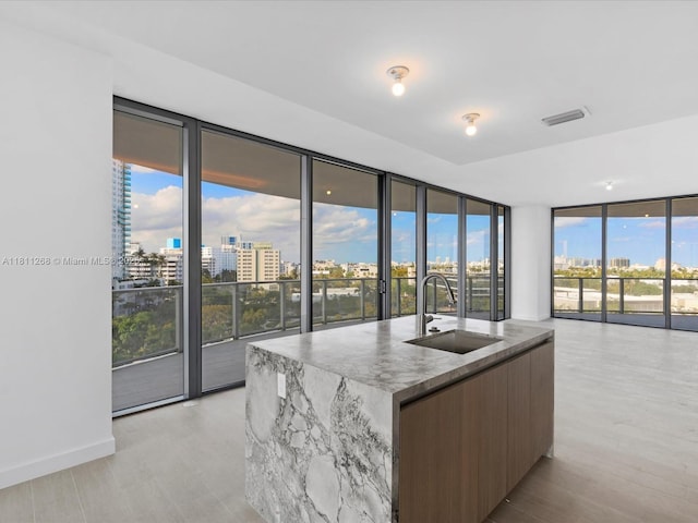 500 Alton Rd Unit 805, Miami Beach, FL 33139 - kitchen with a sink, modern cabinets, expansive windows, light stone countertops, and a kitchen island with sink