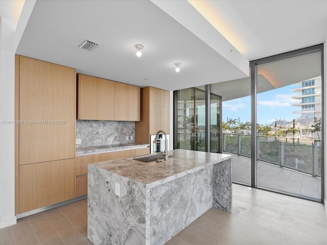 500 Alton Rd Unit 805, Miami Beach, FL 33139 - kitchen featuring a sink, modern cabinets, light stone countertops, decorative backsplash, and floor to ceiling windows