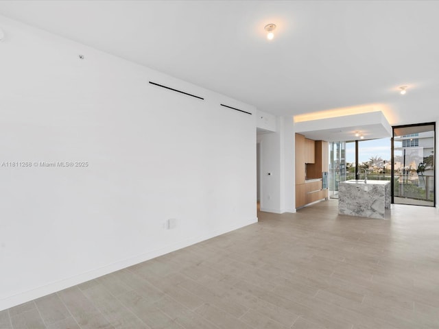 500 Alton Rd Unit 805, Miami Beach, FL 33139 - unfurnished living room featuring expansive windows, baseboards, and light wood-style flooring