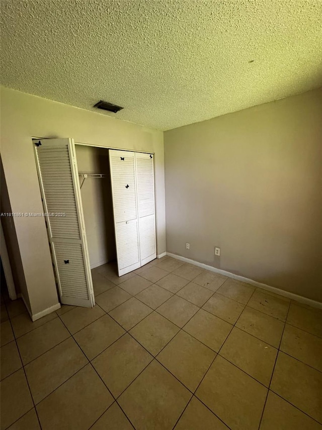 6023 10th Ave N Unit 215, Green Acres, FL 33463 - unfurnished bedroom with tile patterned flooring, a textured ceiling, and a closet