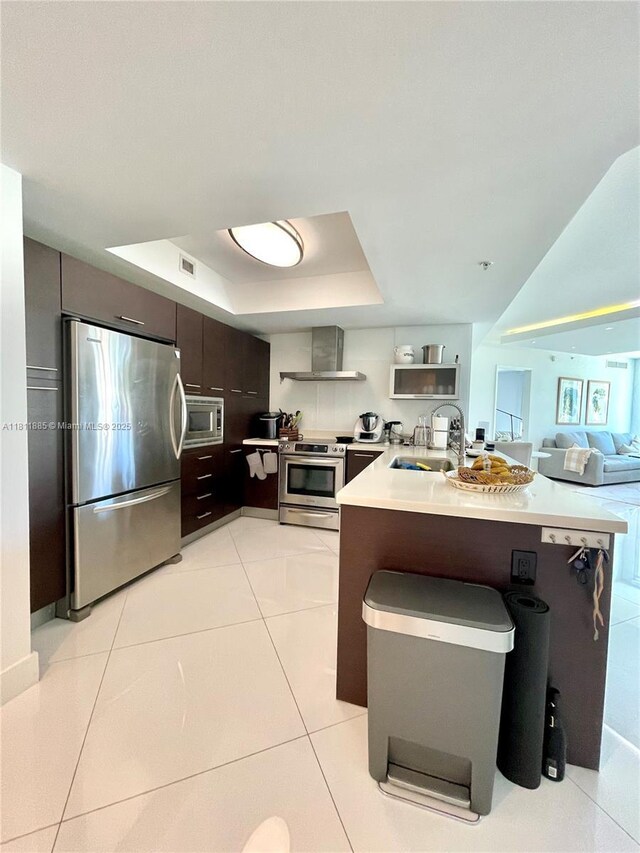 250 Sunny Isles Blvd Unit 3-602, Sunny Isles Beach, FL 33160 - kitchen featuring appliances with stainless steel finishes, wall chimney range hood, a sink, a tray ceiling, and dark brown cabinets
